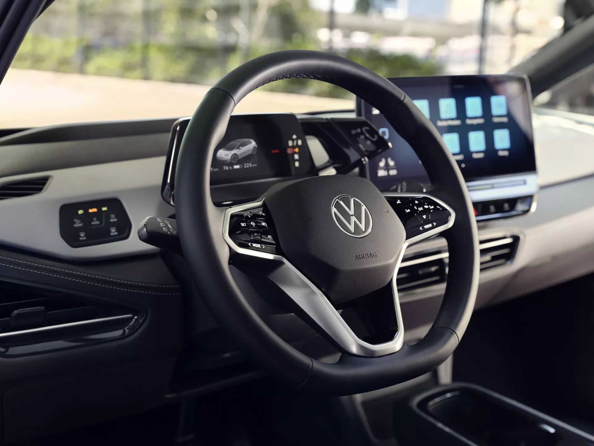 Interiérový pohled na VW ID.3 1. generace facelift 2023 s moderním volantem s plochým dnem a chromovým emblémem, digitálním přístrojovým panelem a velkou obrazovkou infotainment systému, demonstrující pokročilé ovládací systémy a luxusní designové prvky