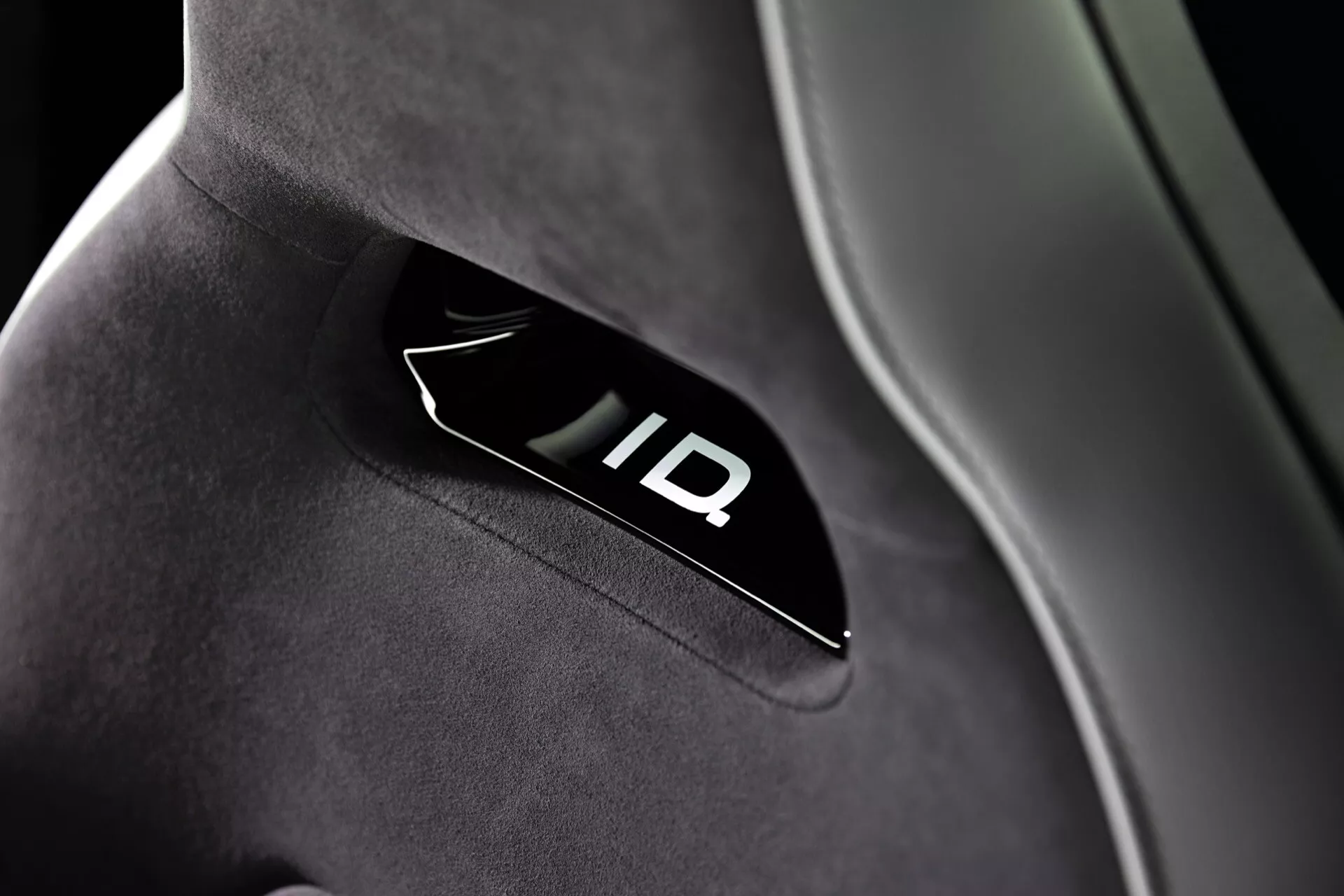 Detailní pohled na podsvícené logo 'ID' na kvalitním potahu sedadla automobilu ve VW ID.3 rok 2023 (první generace facelift), zdůrazňující moderní interiérový design a pokročilou technologii