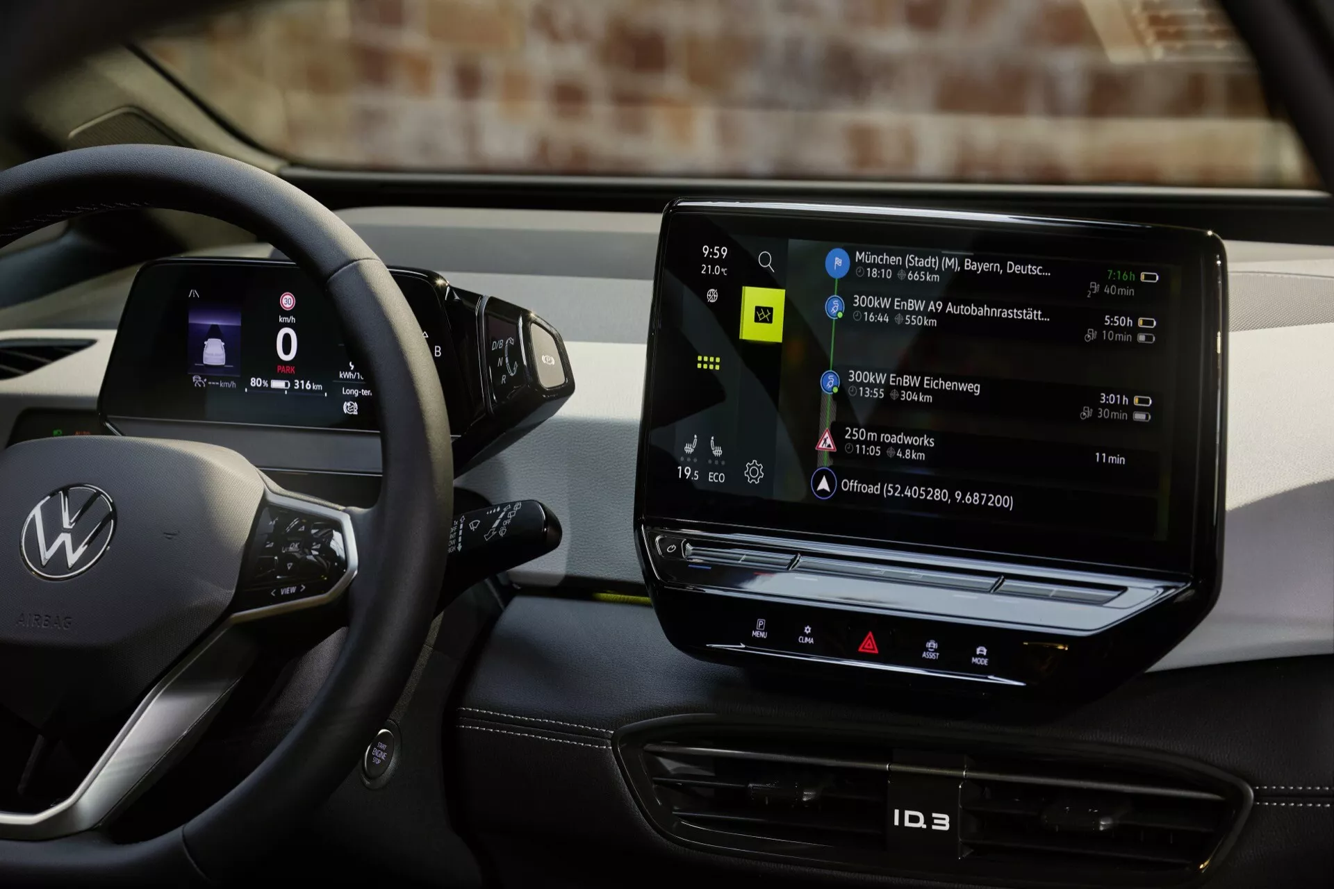 Interiér vozu Volkswagen ID.3 ročník 2023 s pohledem na stranu řidiče, volant s logem, ovládacími tlačítky a výrazným vertikálním dotykovým informačním systémem zobrazujícím mapu nabíjecích stanic, odrážející moderní technologii elektrických vozidel.