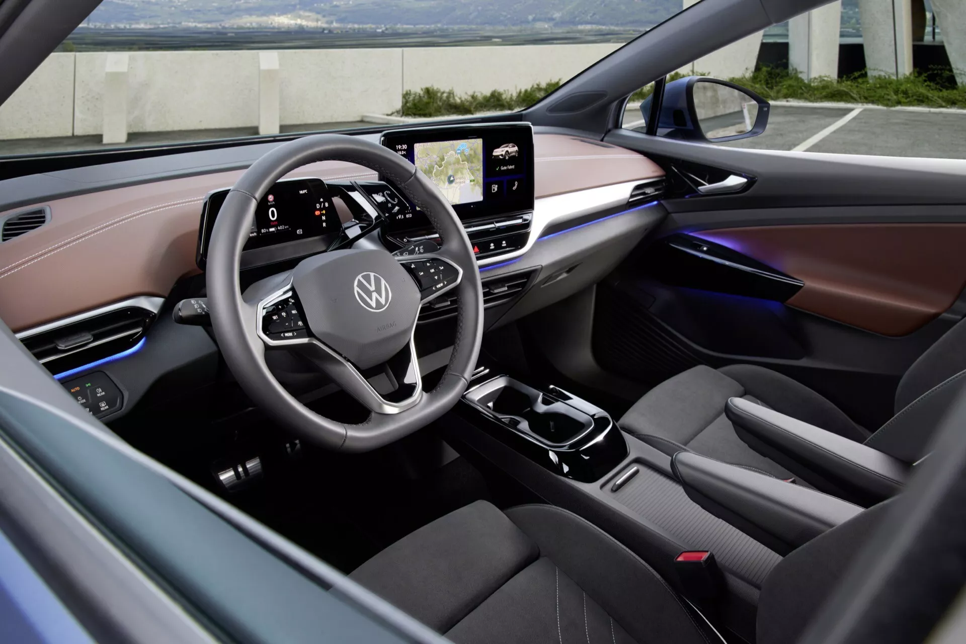 Pohled na interiér VW ID.5 2022 1. generace z předního pasažérového sedadla, zvýrazňující multifunkční volant s dotykovým ovládáním, integrovanou digitální palubní desku, centrálně umístěný dotykový infotainment systém, moderní středovou konzoli s řadicí pákou, ambientní osvětlení, prémiové materiály, ergonomické řidičovo sedadlo, standardní bezpečnostní prvky a panel moderního klimatizačního systému.