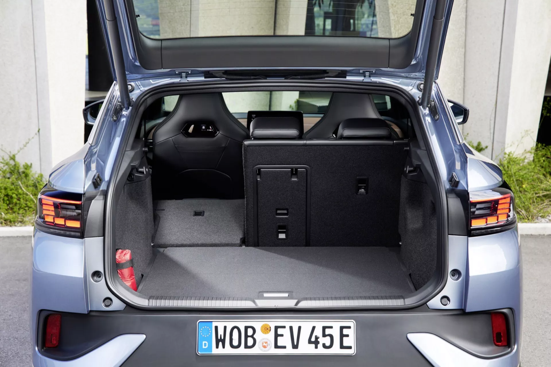 Zadní pohled na VW ID.5 2022 první generace s otevřeným zavazadlovým prostorem, který odhaluje prostornou nakládací plochu s plochým podlahou a sklopenými zadními sedadly. Obrázek zdůrazňuje zvětšenou kapacitu zavazadlového prostoru, moderní LED zadní světla a označení elektrického vozidla na centrálně umístěné registrační značce. Další funkce zahrnují zasouvatelný kryt zavazadlového prostoru, vnitřní úložné prostory a chromované ozdobné prvky.