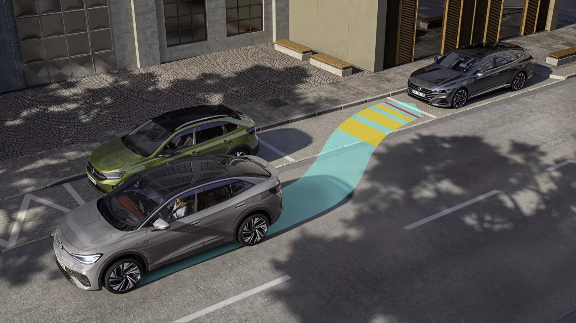 Pohled z vysokého úhlu na dvě moderní elektrická SUV prezentující pokročilé technologické funkce, jako je překrytí rozsahu senzorů jednoho z vozidel. Přední vozidlo v metalické stříbrné barvě zobrazuje modré a žluté grafické zobrazení svého asistenčního systému řidiče, zdůrazňující jeho pole detekce. Za ním je zaparkované tmavší SUV, možná tmavě šedé nebo černé, v městském prostředí za silného slunečního svitu.