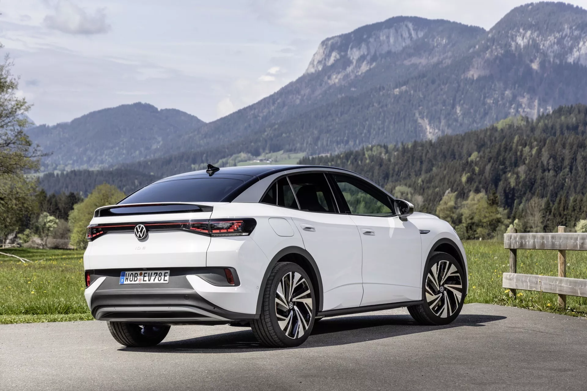 Boční a zadní tříčtvrteční pohled na hatchback VW ID.5 z roku 2022 (1. generace), který ukazuje moderní design s horizontálními LED koncovými světly, plnošířkovým světelným pruhem, vysoko umístěnou brzdovou svítilnou integrovanou do zadního spoileru, elegantními liniemi oken, zapuštěnými klikami dveří, vícepaprskovými slitinovými koly a panoramatickou střechou. Automobil je vyfotografován venku v přírodním prostředí v pozadí, což naznačuje všestrannost v různých jízdních podmínkách.