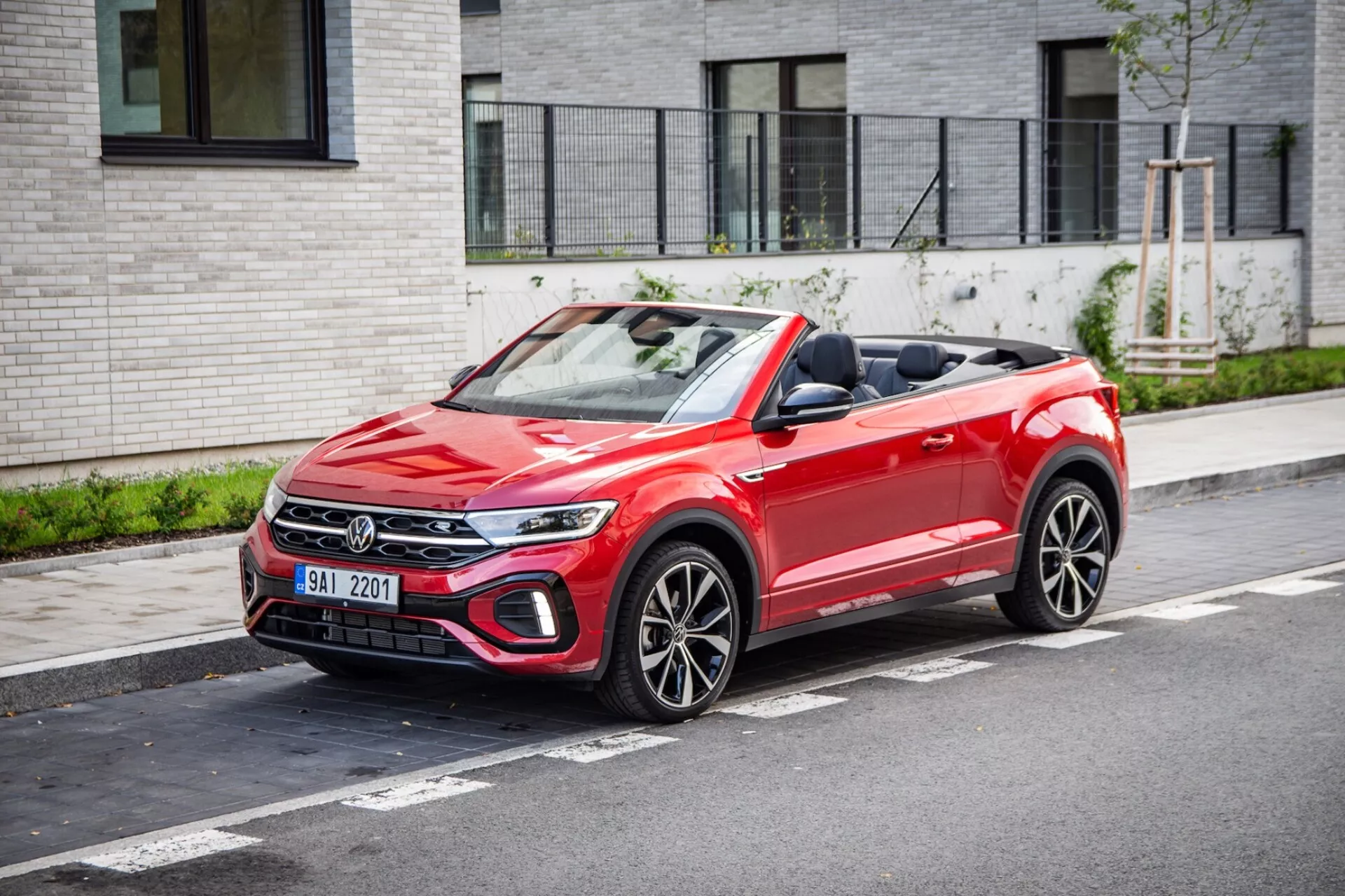Volkswagen T-Roc Cabriolet 2022 parkovaný na městské ulici s výhledem na přední mřížku, LED světlomety, skládací textilní střechu a sportovní kola s více paprsky