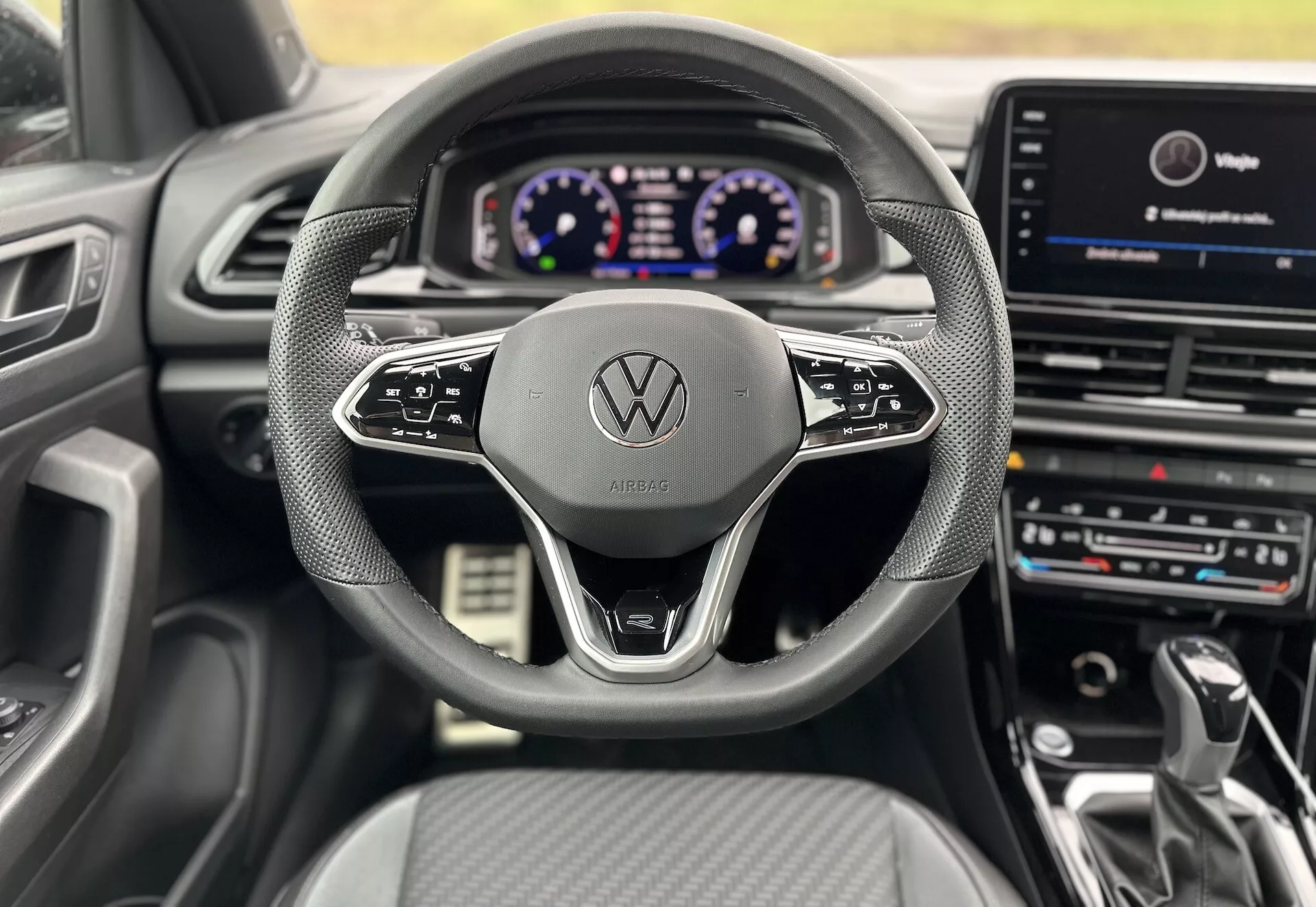 Pohled z interiéru z pozice řidiče Volkswagen T-Roc Cabriolet 2022, zobrazující volant, digitální přístrojovou desku a centrální infotainment systém