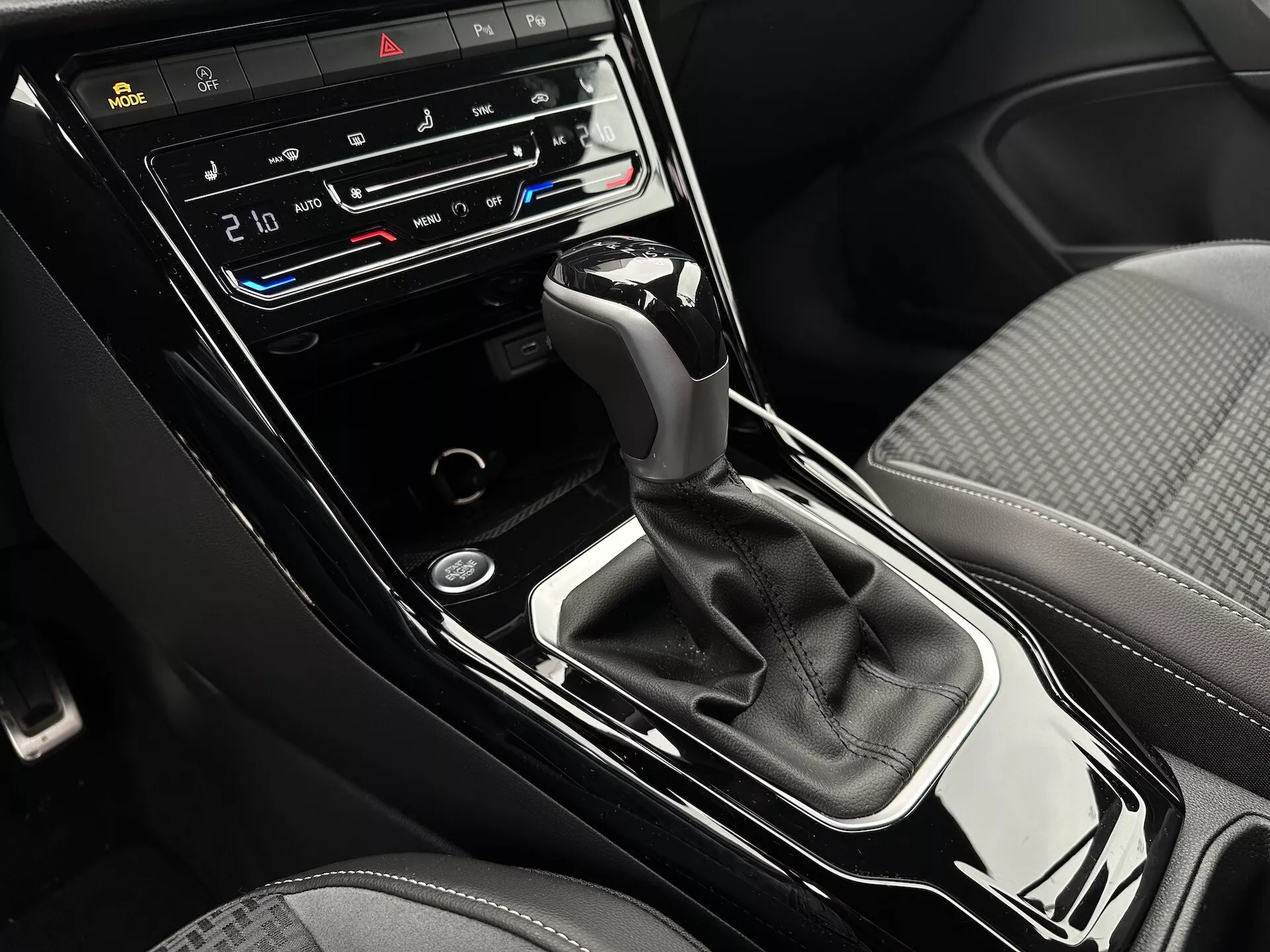 Detailní pohled na středovou konzolu VW T-Roc Cabriolet 2022 s automatickou převodovkou, dvouzónovou klimatizací, tlačítky pro vyhřívání a ventilaci sedadel a ovládacím displejem