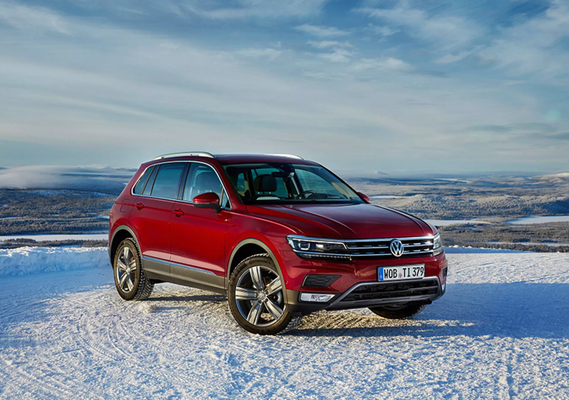 Červený Volkswagen Tiguan 2016 ve sněhové venkovní krajině s denním přirozeným osvětlením, přední mřížkou, LED světlomety, chromovanými akcenty a slitinovými koly.