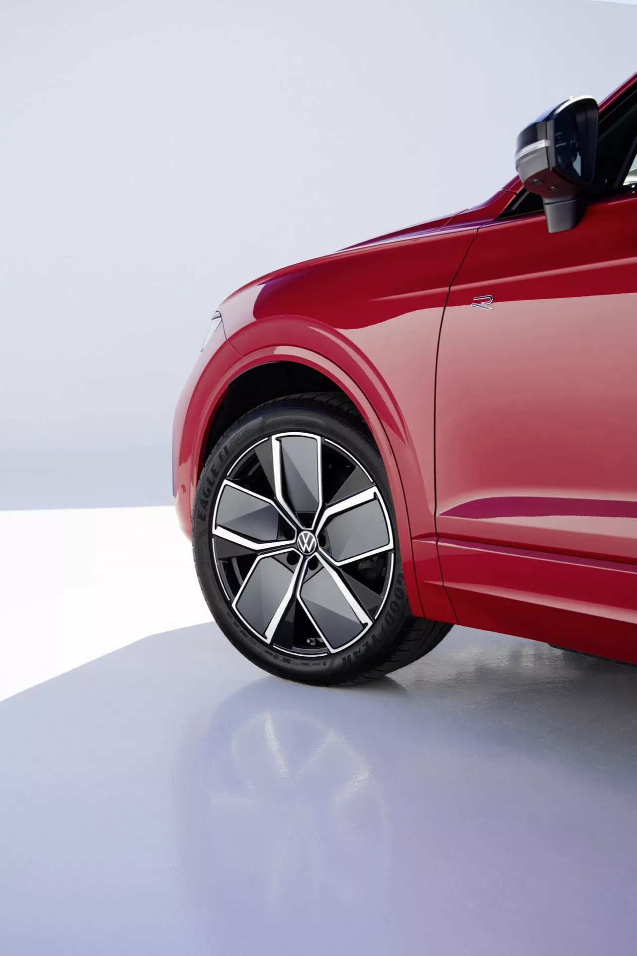 Pohled na přední čtvrtinu řidičovy strany VW Touareg Facelift 2023 zdůrazňující slitinové kolo, nízkoprofilovou pneumatiku a dynamické linie karoserie pod profesionálním studiovým osvětlením