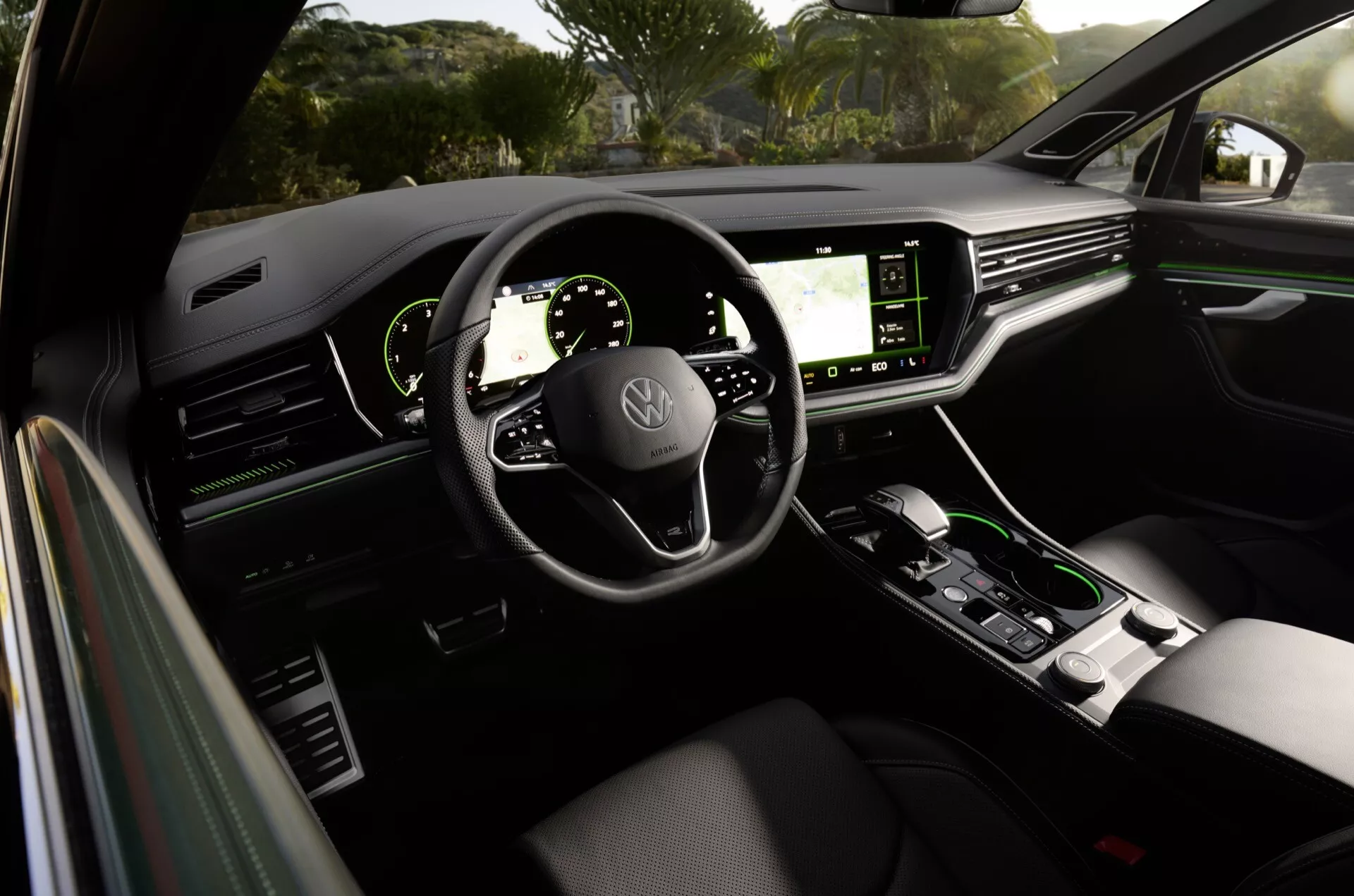 Interiér Volkswagen Touareg 2023 z pohledu ze zadního sedadla ukazující palubní desku, digitální displeje, volant s ovládacími prvky a středovou konzoli v moderním a luxusním designu