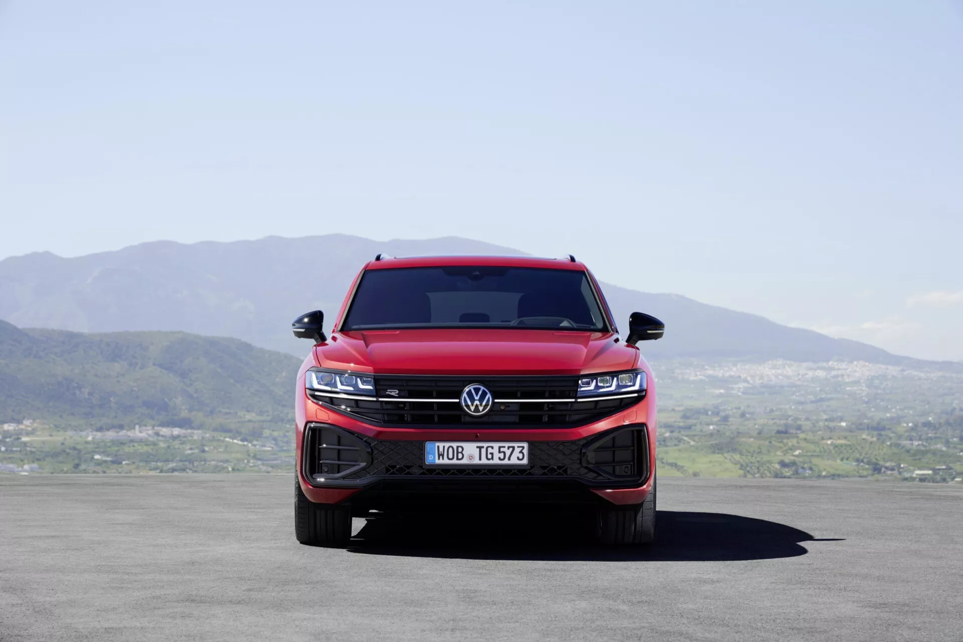 Pohled zepředu na červený Volkswagen Touareg III facelift 2023 ukazující integrovanou mřížku a shluky LED světlometů, které zvýrazňují dominance vozidla a moderní technologické funkce