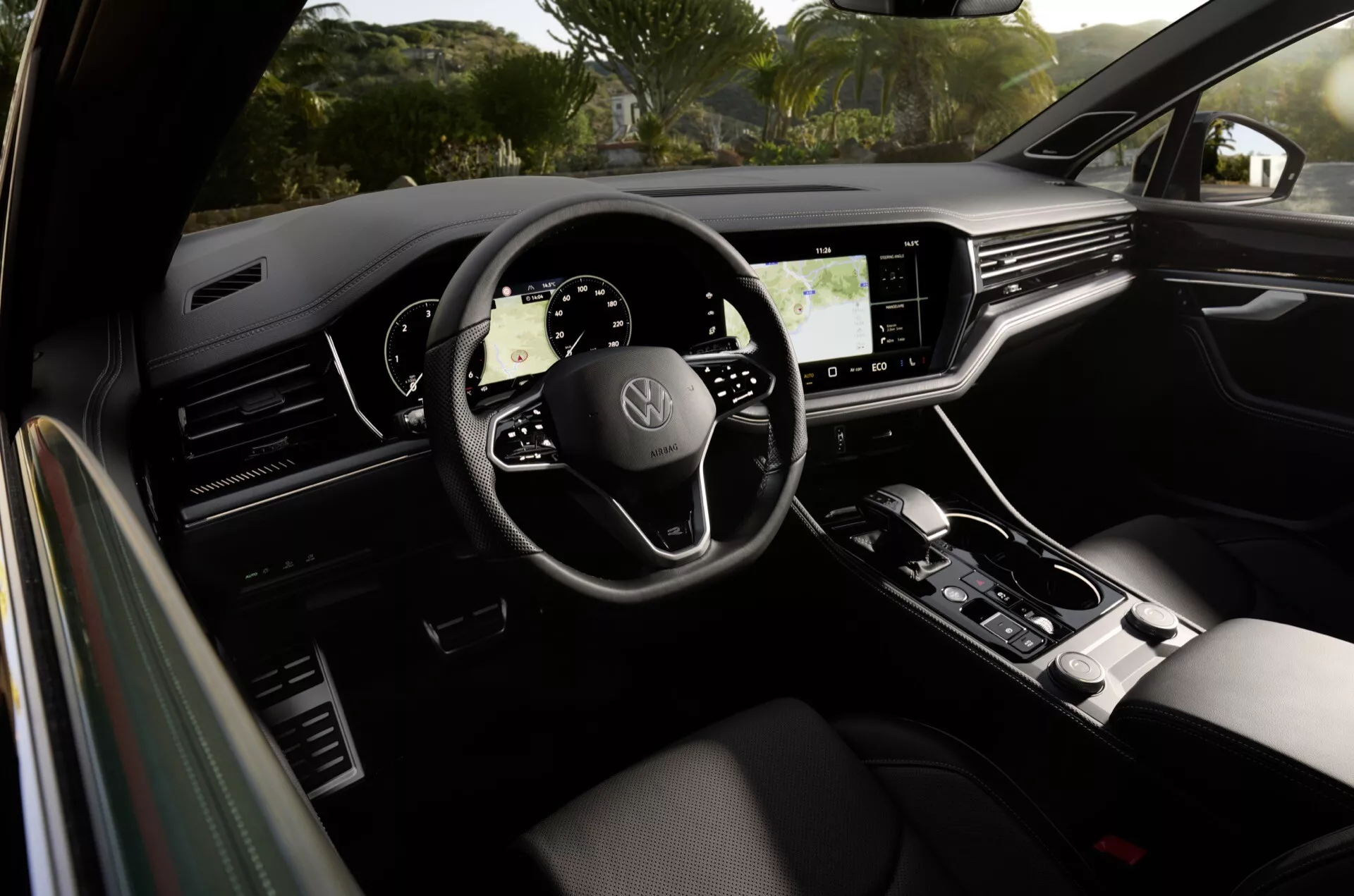 Interiér Volkswagen Touareg 2023 ukazující volant se třemi rameny s logem značky, plně digitální přístrojový panel, velký dotykový informační displej a stylovou volící páku, zdůrazňuje moderní design auta a pokročilé technologické funkce
