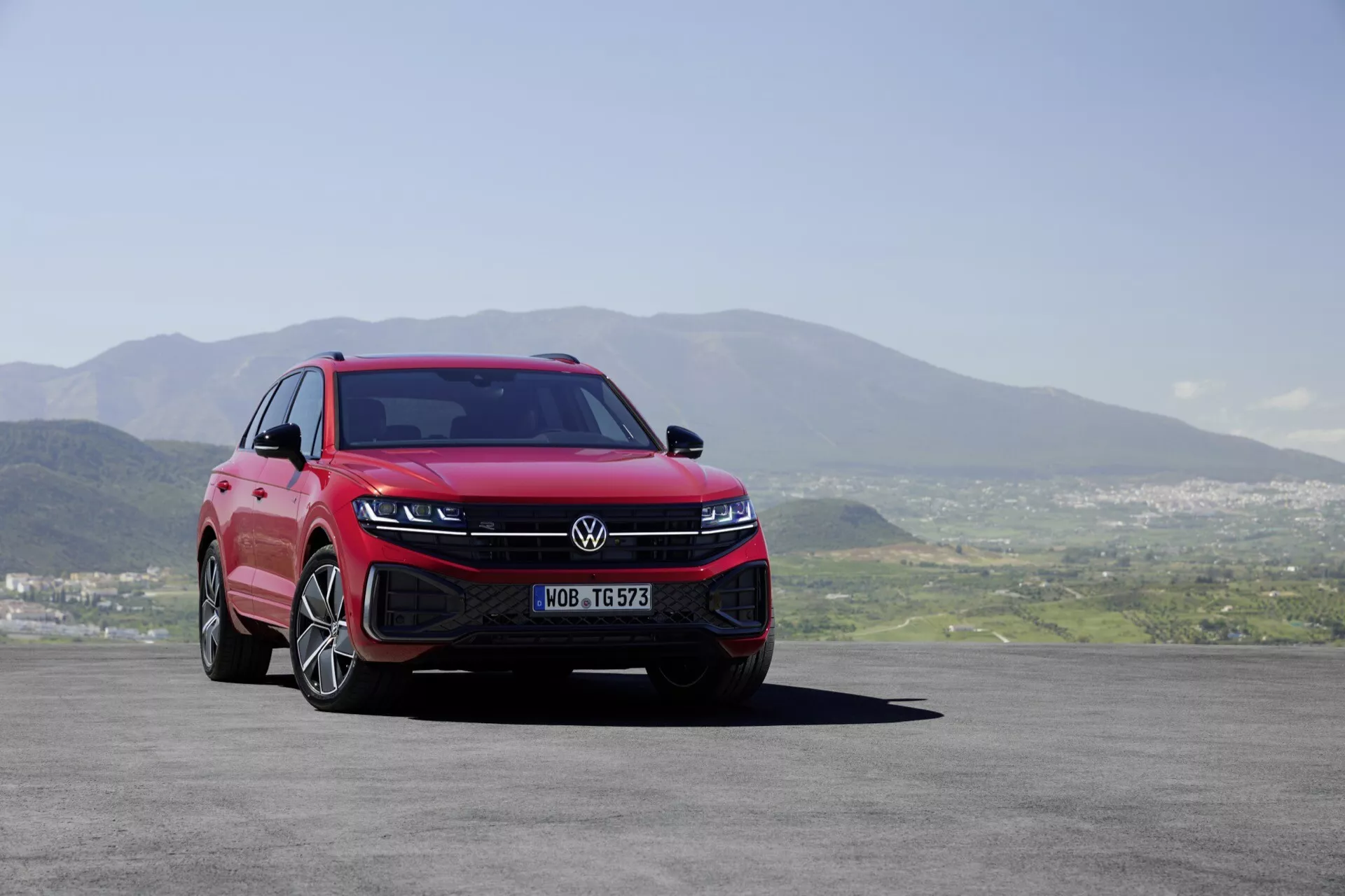 Volkswagen Touareg 2023 (III-Facelift) prezentuje svůj moderní design z nízkého úhlu zepředu a z boku, zdůrazňuje LED světlomety, sportovní přední nárazník, aerodynamickou mřížku a kola z lehkých slitin proti scénickému pozadí.
