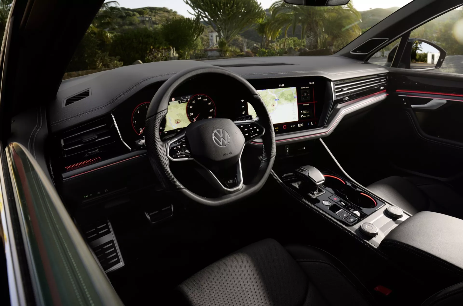 Interiér Volkswagenu Touareg 2023 z pohledu zadního cestujícího, volant s logem, digitální přístrojová deska a dotyková centrální konzola