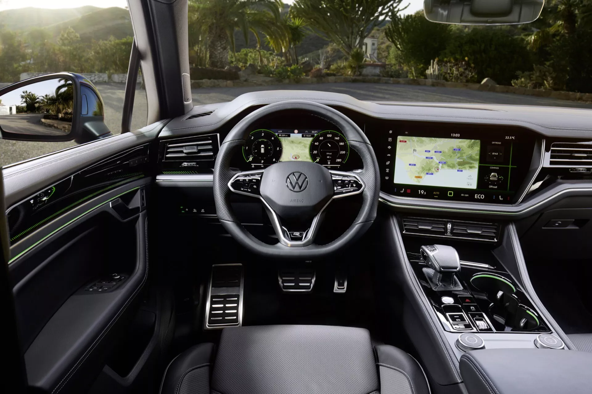 Interiér VW Touareg 2023 z pohledu řidiče s volantem s logem Volkswagen, moderním přístrojovým panelem, vysoce rozlišovacím dotykovým infotainment systémem, ovládáním klimatizace a luxusními designovými prvky